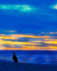 A man and his dog are silhouetted against a dark blue sea and an orange sunset.